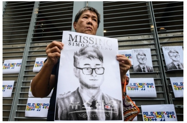 한 홍콩시민이 전 홍콩주재 영국 영사관 직원인 사이먼 쳉의 포스터를 들고 있다.사이먼 쳉은 중국 비밀 경찰에 8월  체포돼 2주간 갖은 고문을 당했다고 그의 페이스북에 묘사하고 있다(사진-워싱턴 포스트)