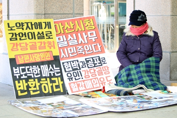 호소인 원옥분 할머니가 홀로 아산시청 현관 앞에서 1인 시위를 하고 있다. 관계 공무원과 시의원들의 외면에도 불구하고 차디찬 바닥에 앉아 억울함을 호소하고 있다.