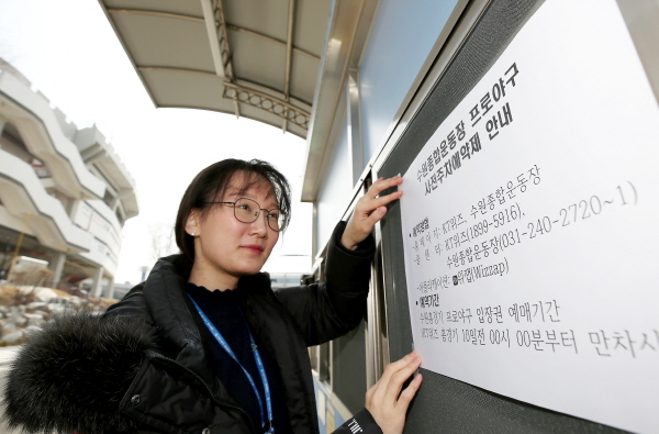 수원도시공사 종합운동장 직원이 남문게이트에 사전주차예약 안내문을 붙이고 있다.