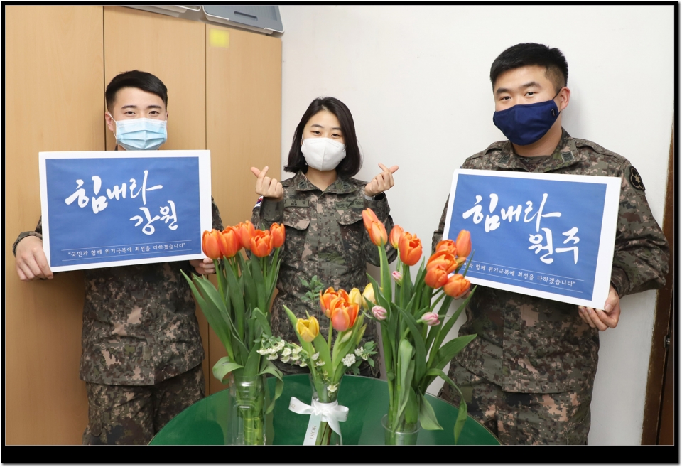 36사단 간부들이 지역 화훼농가를 돕기 위해 구매한 꽃을 사무실에 비치하고 ’힘내라 강원, 힘내라 원주‘ 팻말을 들어 보이고 있다.