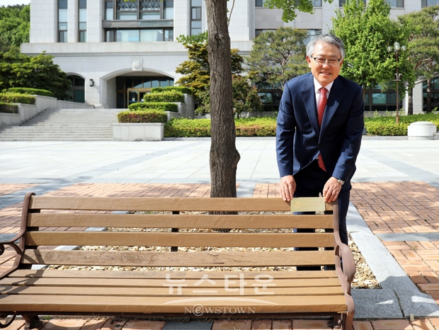 2호 기부자 선문대 배선길 총동문회장이 자신의 명패가 부착된 선문대 본관 앞 야외 벤치 앞에서 포즈를 취하고 있는 모습