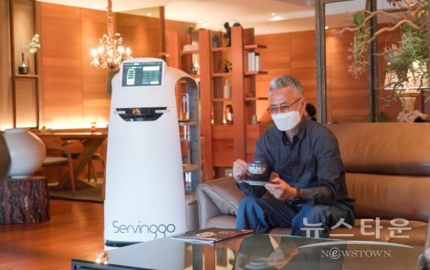 AI 서빙로봇 서빙고가 호텔 이용객에게 음료를 제공하고 있다(사진 : SK텔레콤)