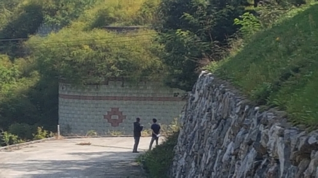 취재기자가 건축사로 부터 자세한 설명을 듣고 있다, 문제의 옹벽도 보인다.