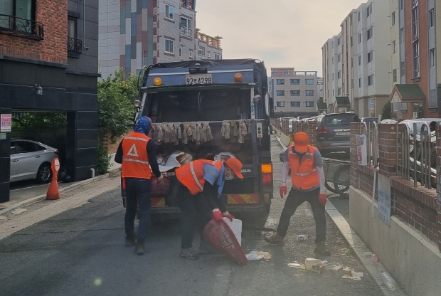 환경미화원과 자원순환과 직원이 이른 아침 쓰레기를 수거해 청소차에 투입하고 있다.