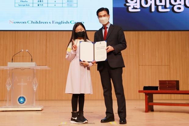 캠프 수료식에서 김일목 총장이 우수 학생에게 총장상을 수여하고 기념사진을 찍고 있다..