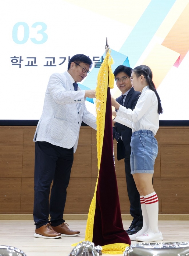 도성훈 인천광역시교육감이 20일 열린 인천아람초등학교 개교기념식에서 정봉남 교장과 김예원(6학년)학생에게 교기를 전달하고 있다.