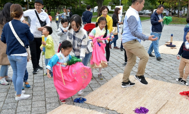 추석명절 호반광장에서 한복입은 어린이가 제기차기를 하고 있다.