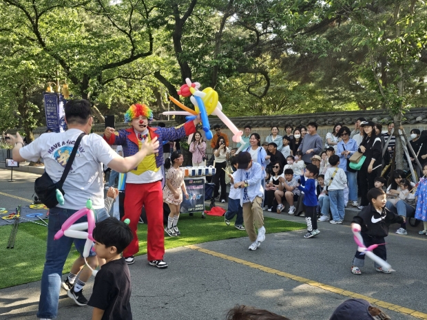대릉원 돌담길 상생마켓서 펼쳐진 거리 공연... 경주 대릉원 돌담길 일원에서 열린 '2025 경주 대릉원 돌담길 상생마켓' 행사에서 광대 복장의 공연자가 어린이들과 함께 풍선 놀이를 하며 관객들의 큰 호응을 얻고 있다.
