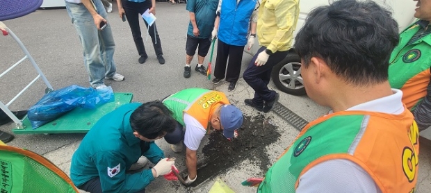 부천시 직원들과 자율방재단원들이 빗물받이 내 퇴적물을 제거하고 있다.
