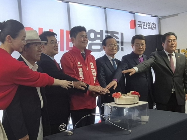 배준영 국회의원과 나란히 김정헌 후보가 케잌 절단식을 하고 있다.