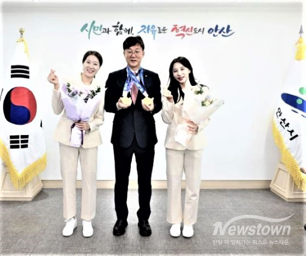 이민근 안산시장(가운데)이 지난 2일 시장실에서 열린 아시안게임 메달 봉납식에서 여자 사브르 단체전 금메달을 획득한 안산시청 소속 서지연·김정미 선수와 기념촬영을 하고 있다. 이 시장은 금메달 두 개를 들어 보이고, 선수들은 꽃다발을 들고 있다. /안산시<br>